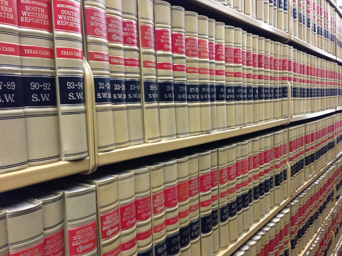 Long rows of bound law reports with red and navy spines on library shelves